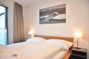 um quarto com uma grande cama branca e 2 candeeiros em Apartment Edelwyss - GriwaRent AG em Interlaken