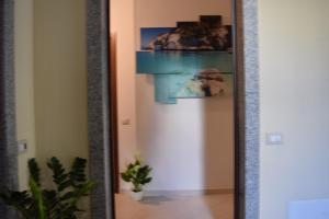 a mirror in a hallway with a picture on the wall at suite the natural color in Selargius