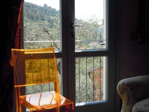 une chaise jaune assise devant une fenêtre dans l'établissement I Freschi, à San Bartolomeo al Mare