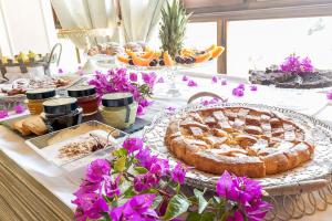 un tavolo con torta e altri prodotti alimentari e fiori di Hotel Villa Calandrino a Sciacca