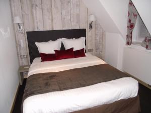 a bedroom with a large bed with red pillows at Hôtel Panorama in Munster