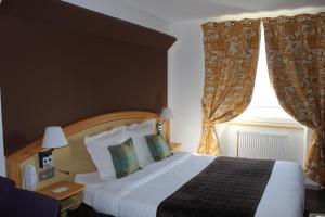 a bedroom with a bed and a window with curtains at Hôtel Panorama in Munster