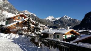 un villaggio ricoperto di neve con montagne sullo sfondo di Hotel Nevada a Campitello di Fassa