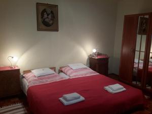 1 dormitorio con 1 cama roja y 2 toallas en GERARDUS apartman, en Budapest