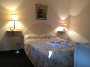 a bedroom with a bed with two robes on it at Alpes Hotel in Punta del Este