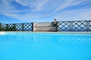 a woman sitting on a fence next to a pool at Corral de Payo Grande in Breña Baja