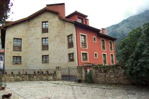 a large house with a stone fence in front of it at Hotel Los Ángeles in Arenas de Cabrales