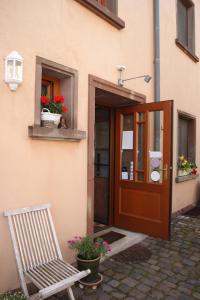 eine Holztür mit einem Stuhl vor einem Gebäude in der Unterkunft Gästehaus 'Alte Bäckerei' Kaffeehaus in Großbundenbach