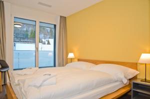 a bedroom with a large white bed with a window at Apartment Gänseblüemli - GriwaRent AG in Interlaken