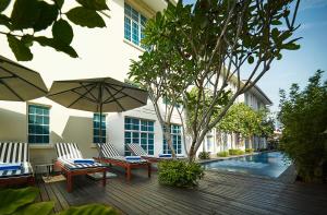 un patio con sillas y sombrillas junto a una piscina en The Edison George Town, en George Town