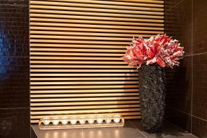 a vase with red flowers sitting on a counter at G Design Hotel in Ljubljana
