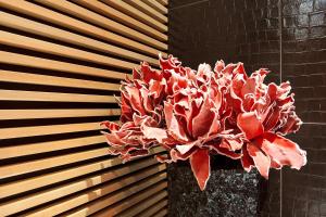 a red plant in a vase on a wall at G Design Hotel in Ljubljana