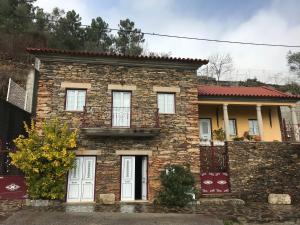 a stone house with white doors and a brick wall at Casa da Escola Antiga in Manteigas