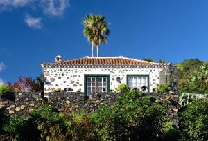 Corral de Payo Casita Blanca في برينيا باخا: منزل على نخلة فوق جدار حجري