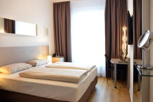 a bedroom with a bed and a desk and a window at Arthotel Munich in Munich
