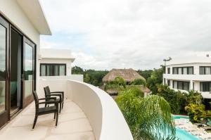 a balcony with two chairs and a swimming pool at Mak Nuk Village - Clothing Optional in Tulum