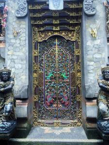 Una puerta de oro con dos estatuas delante. en Alamanda Accomodation, en Ubud