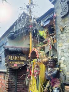 eine Statue vor einem Gebäude mit einem Schild in der Unterkunft Alamanda Accomodation in Ubud