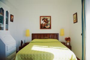 ein Schlafzimmer mit einem Bett mit einer grünen Decke in der Unterkunft Milfontes Villa in Vila Nova de Milfontes