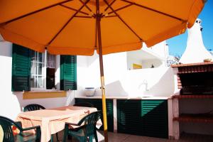 ein orangefarbener Regenschirm auf einem Tisch in der Unterkunft Milfontes Villa in Vila Nova de Milfontes
