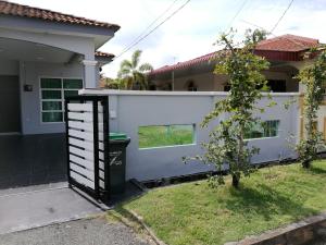 a house with a white fence and a trash can at Barakah Homestay in Alor Setar