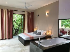 a bedroom with a bed and a bath tub at Lake House Hikka in Hikkaduwa