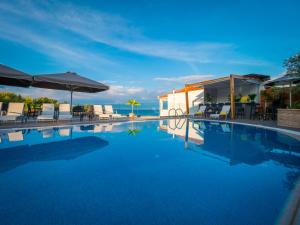 a swimming pool with chairs and umbrellas and the ocean at Panorama Apartments in Chrani