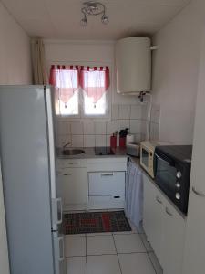 a small kitchen with a refrigerator and a window at Les Cigales in Narbonne-Plage
