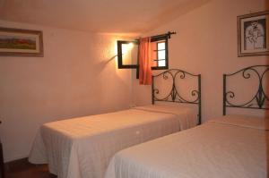 テッラヌオーヴァ・ブラッチョリーニにあるIl Belvedere house in the Tuscan countrysideの白いシーツと窓が備わるベッド2台付きの客室です。