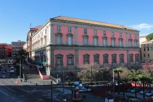 a pink building on a street with cars parked in front at Al 68 Di Piazza Cavour in Naples