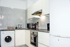a kitchen with white cabinets and a washer and dryer at Pafia 3 Holiday Apartment in Paphos City