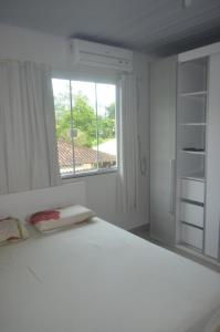 Un dormitorio blanco con una cama grande y una ventana en Sobrado, en Itapema