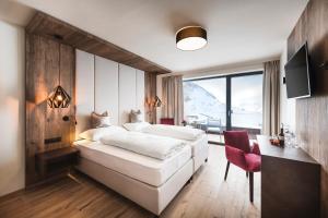 sypialnia z dużym białym łóżkiem i biurkiem w obiekcie Mooshaus Winterresort w mieście Kühtai