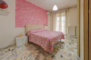 ein Schlafzimmer mit einem Bett und einer rosa Wand in der Unterkunft Casa Vacanza Shanaia in Pietra Ligure