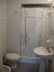 a bathroom with a toilet a sink and a shower curtain at Hospedaje Acacia in Pinamar +49 photos