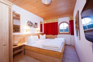 - une chambre avec un lit dans une pièce dotée de rideaux rouges dans l'établissement Haus Brigitte, à Nauders