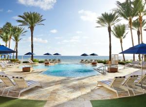 a pool at the beach with chairs and palm trees at Eau Palm Beach Resort & Spa in Palm Beach