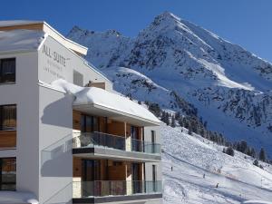 um edifício com uma montanha coberta de neve ao fundo em Modern ski-in Appartement 2020m Kühtai em Kühtai