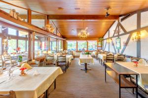 un restaurante con mesas y sillas blancas y ventanas en Hotel Restaurant Möve, en Faulensee