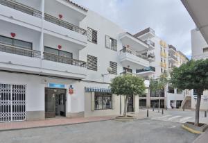 een wit gebouw met bomen ervoor bij All Suite Ibiza Aparthotel in San Antonio