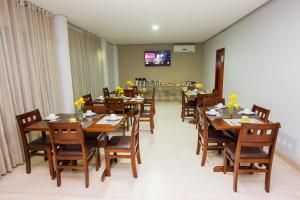 a restaurant with wooden tables and chairs with yellow flowers on them at Pousada Vila da Mata in Canaã dos Carajás