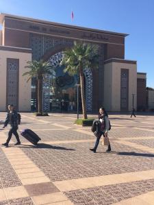 une femme marchant devant un bâtiment avec bagages dans l'établissement Appartement Elias Marrakech, à Marrakech