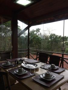 une table en bois avec des assiettes et des serviettes au-dessus dans l'établissement Guaramiranga Apart Monte Verde, à Guaramiranga