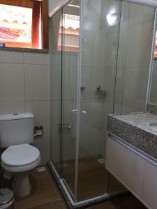 a bathroom with a toilet and a glass shower at Guaramiranga Apart Monte Verde in Guaramiranga