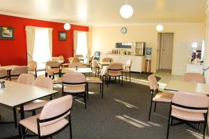 a dining room with tables and chairs and a kitchen at Motel 359 in Tamworth