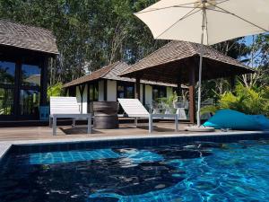 a swimming pool with two chairs and an umbrella at Koyao Bay Pavilions - SHA Extra Plus in Ko Yao Noi
