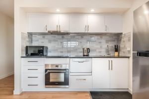 a kitchen with white cabinets and a black oven at Apartments on Fraser Bicheno in Bicheno
