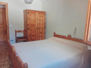 ヴァルディデントロにあるChalet Biancoのベッドルーム1室(大型ベッド1台、木製キャビネット付)