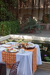 a table with plates of food on it next to a pond at Samode Haveli in Jaipur