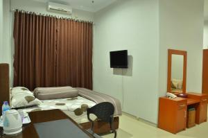 a bedroom with a bed and a desk and a television at Surya Darma Homestay in Yogyakarta